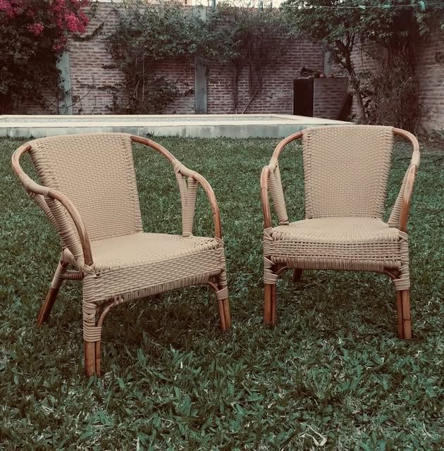 Dos sillones de caña restaurados, apoyados sobre el pasto